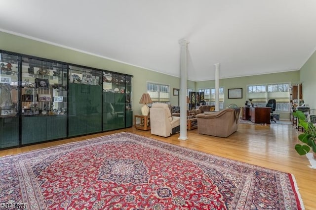 living area featuring vaulted ceiling, decorative columns, and wood finished floors