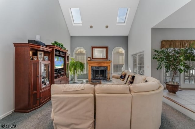 living area with a skylight, carpet, a premium fireplace, and high vaulted ceiling