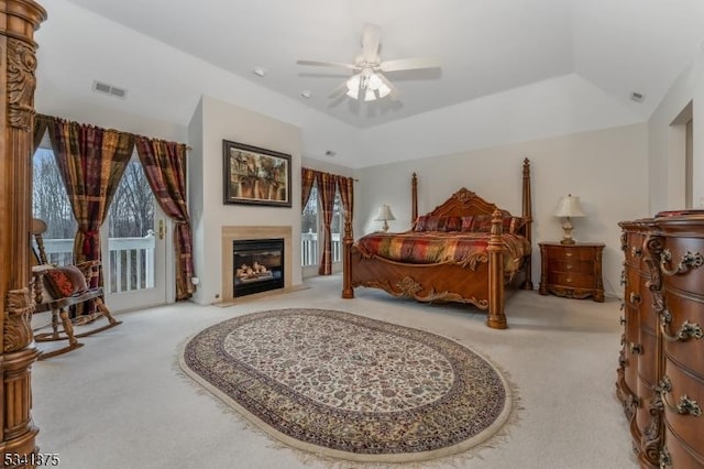 bedroom featuring visible vents, a fireplace with flush hearth, access to exterior, carpet, and a tray ceiling