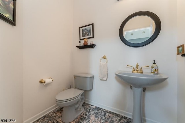 half bath featuring baseboards and toilet