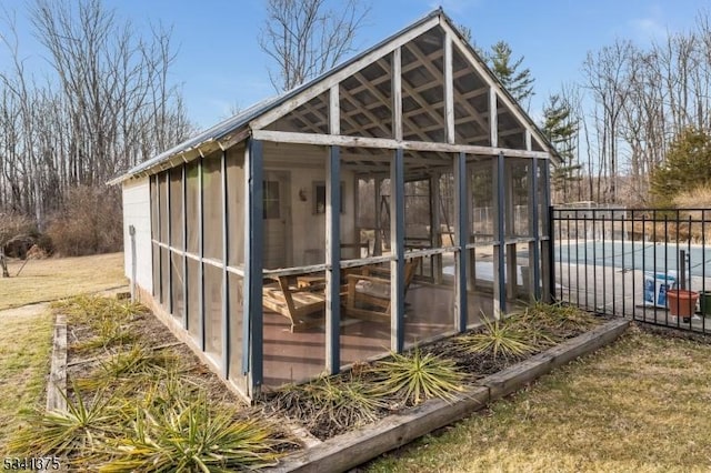 view of outdoor structure featuring a sunroom, fence, and a fenced in pool