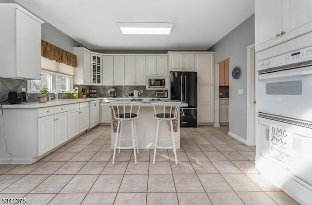 kitchen featuring white appliances, a kitchen island, a breakfast bar, and light countertops