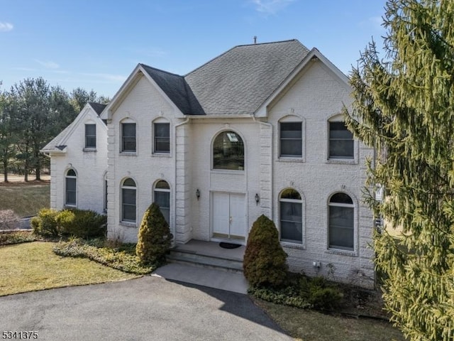 view of front of property featuring a shingled roof and brick siding