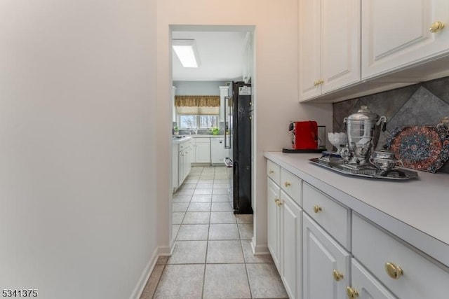 interior space featuring white cabinetry, light countertops, backsplash, and light tile patterned flooring