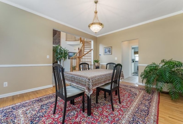 dining area with ornamental molding, light wood-type flooring, and baseboards