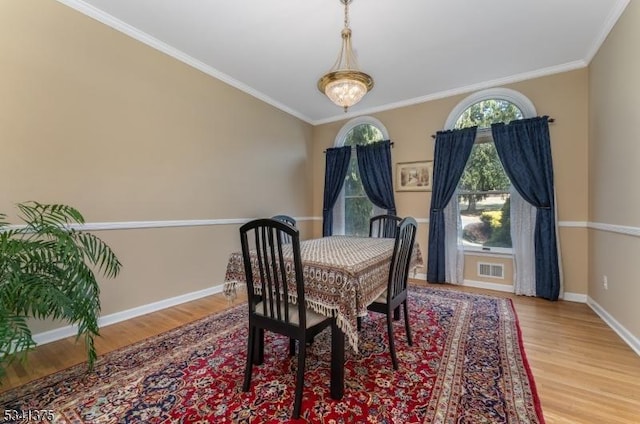 dining room with ornamental molding, visible vents, baseboards, and wood finished floors