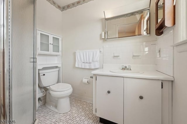 bathroom with vanity, a shower with door, tile patterned floors, toilet, and backsplash