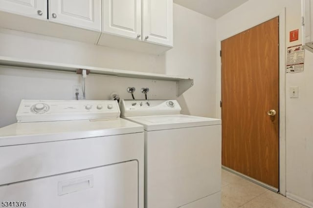 clothes washing area with light tile patterned floors, cabinet space, and washer and clothes dryer