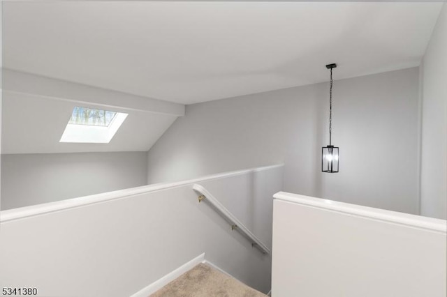 stairs with lofted ceiling with skylight, carpet flooring, and baseboards