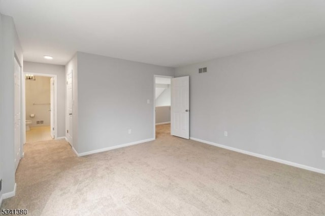 unfurnished bedroom with baseboards, connected bathroom, visible vents, and light colored carpet