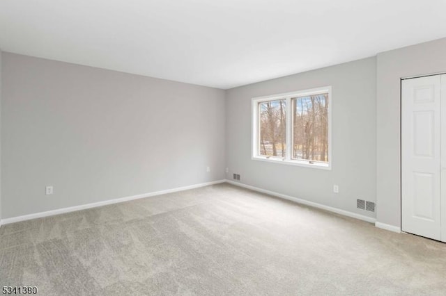 unfurnished room with carpet floors, baseboards, and visible vents