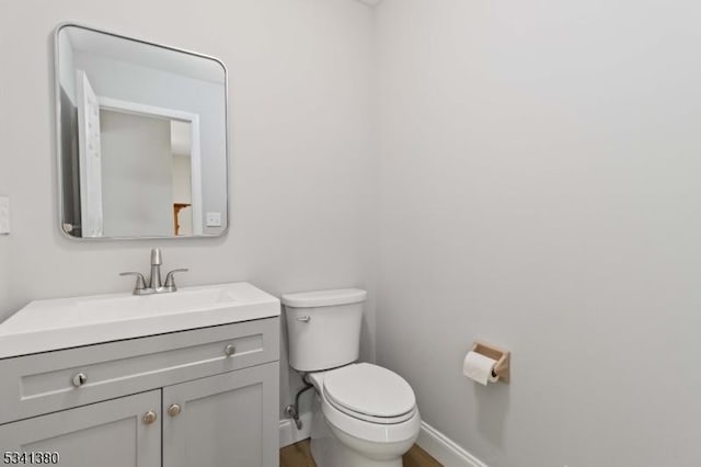 bathroom with wood finished floors, vanity, toilet, and baseboards