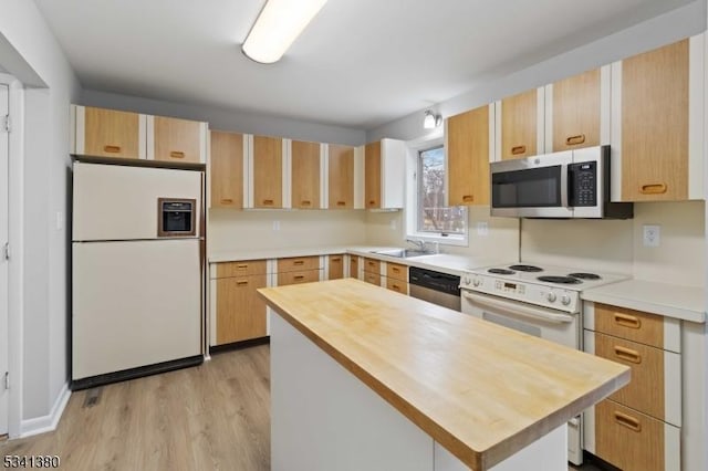 kitchen featuring light brown cabinets, a sink, wooden counters, appliances with stainless steel finishes, and light wood finished floors