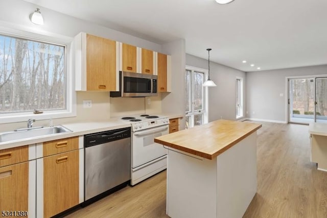 kitchen with light wood-style flooring, a sink, wood counters, appliances with stainless steel finishes, and pendant lighting