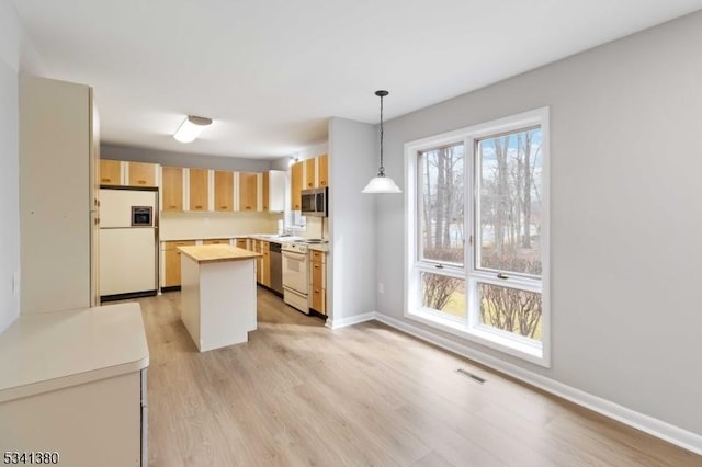 kitchen with white appliances, visible vents, a healthy amount of sunlight, light wood-style floors, and light brown cabinets