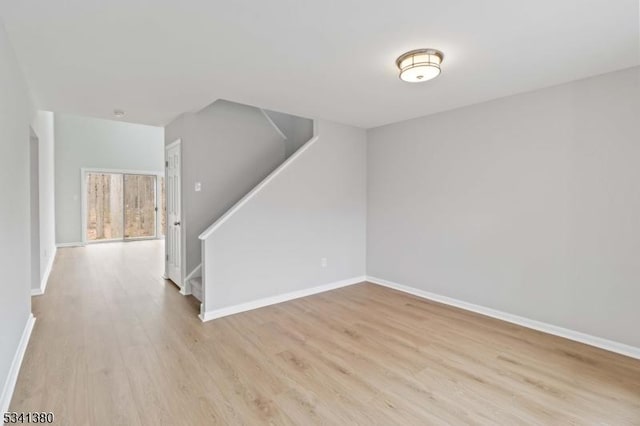 interior space featuring light wood finished floors, stairway, and baseboards