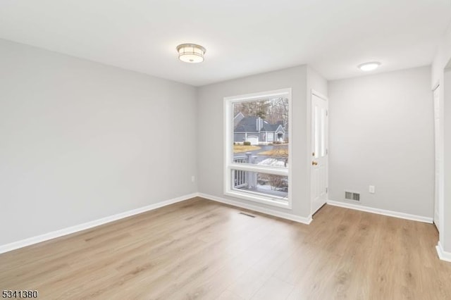 empty room with light wood-type flooring, baseboards, and visible vents