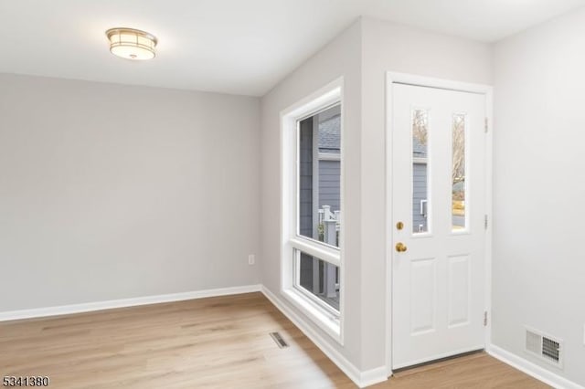 foyer featuring light wood-style flooring, visible vents, and baseboards