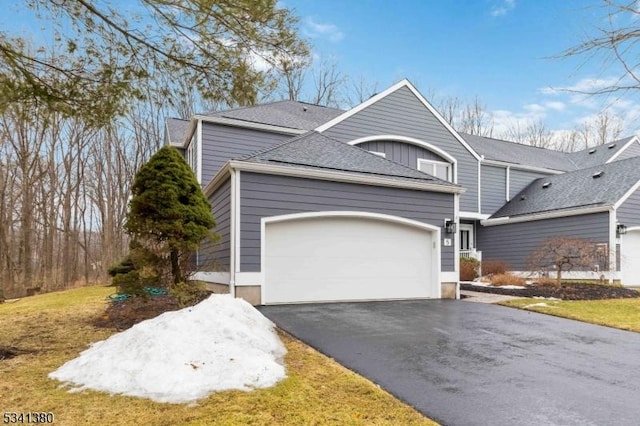 view of front of property with a garage, aphalt driveway, and roof with shingles