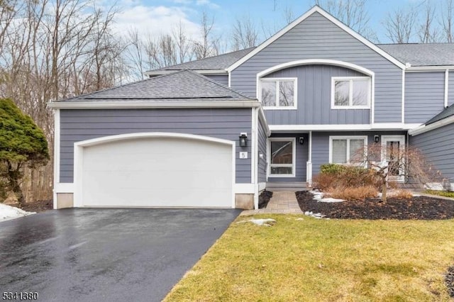 view of front of property with an attached garage, a front yard, aphalt driveway, and roof with shingles