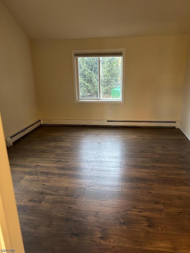 spare room featuring a baseboard radiator and dark wood finished floors