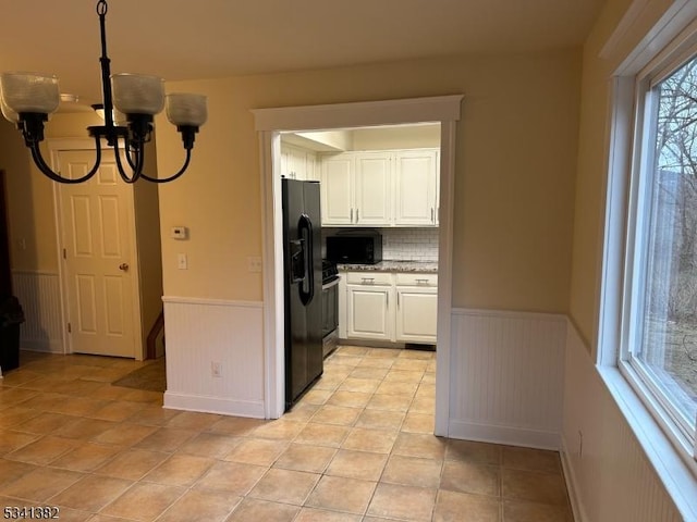 kitchen featuring a chandelier, wainscoting, black appliances, white cabinetry, and light tile patterned flooring