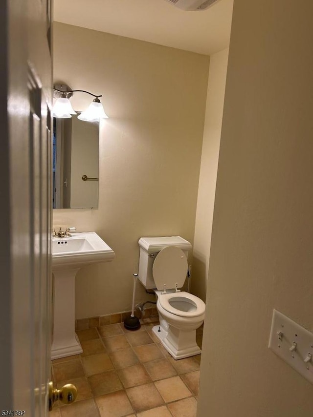 half bathroom with visible vents, tile patterned flooring, toilet, and baseboards