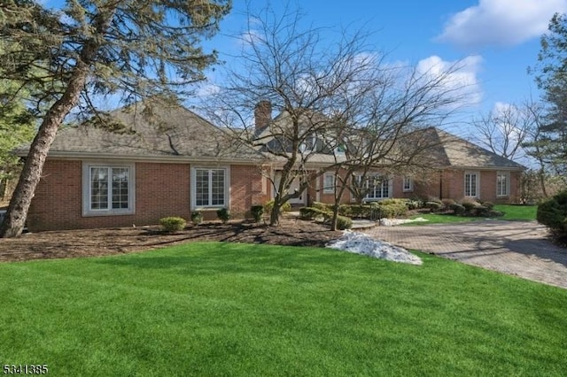 view of front of property with brick siding, a chimney, and a front lawn