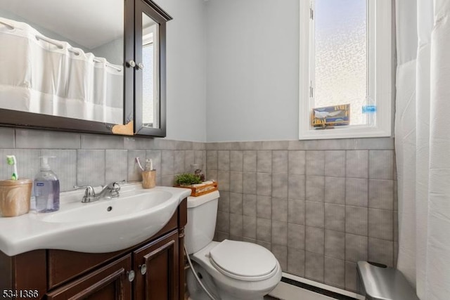 bathroom with tile walls, a baseboard radiator, curtained shower, toilet, and vanity