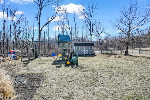 view of play area featuring fence, a storage unit, a lawn, and an outdoor structure