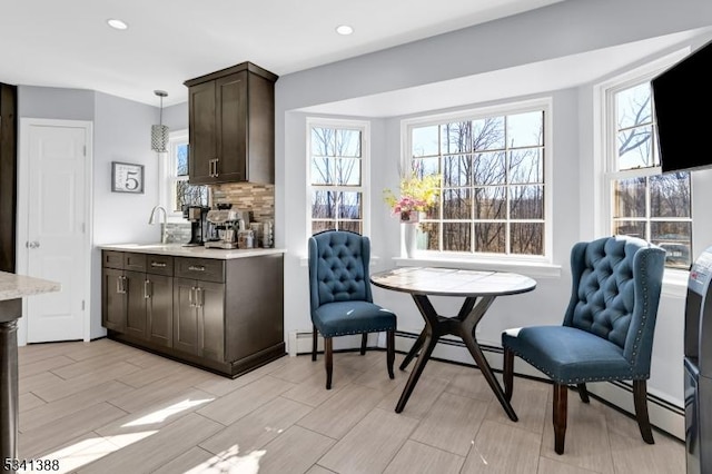 kitchen with dark brown cabinets, backsplash, light countertops, and a healthy amount of sunlight