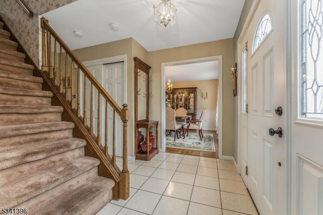 entrance foyer featuring a chandelier, light tile patterned floors, stairway, and baseboards