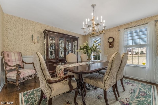 dining area with wallpapered walls, a notable chandelier, and wood finished floors