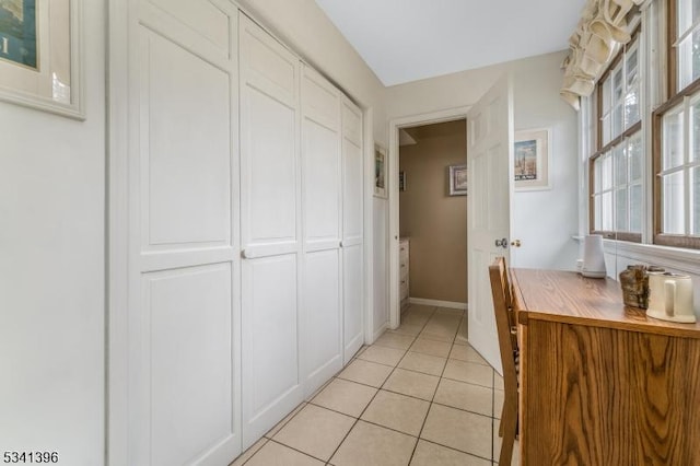 corridor with baseboards and light tile patterned floors