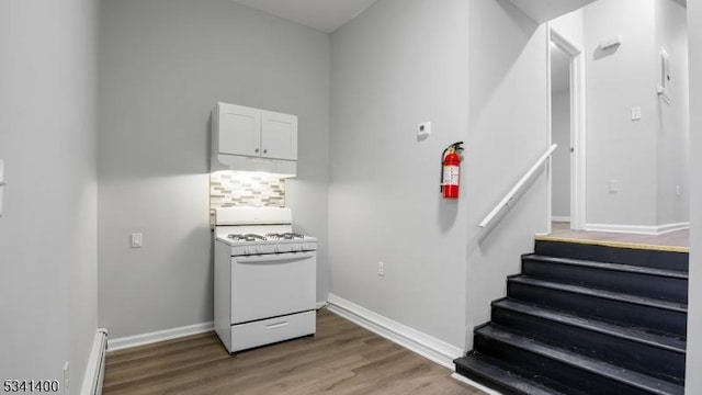 stairs featuring a baseboard radiator, baseboards, and wood finished floors