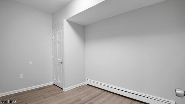 empty room with baseboards, baseboard heating, and wood finished floors