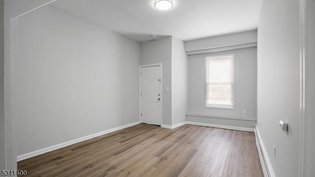 spare room featuring baseboard heating, wood finished floors, and baseboards