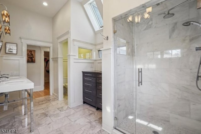 full bathroom with a marble finish shower, marble finish floor, a skylight, and vanity