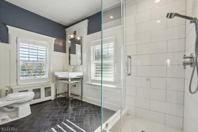 bathroom with toilet, a healthy amount of sunlight, and a shower stall