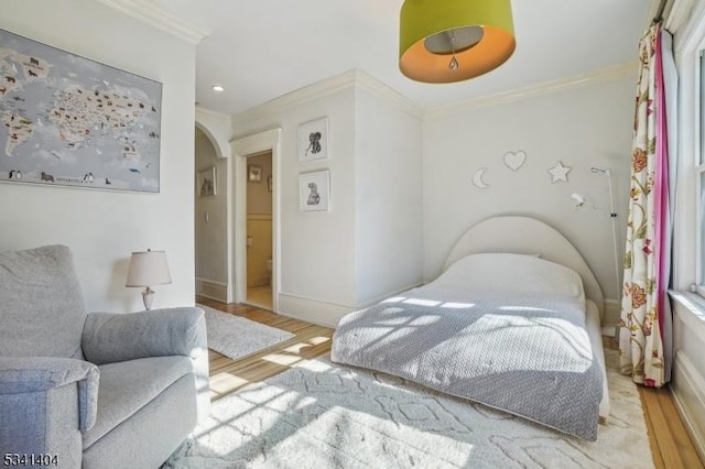 bedroom with ornamental molding, wood finished floors, recessed lighting, arched walkways, and baseboards