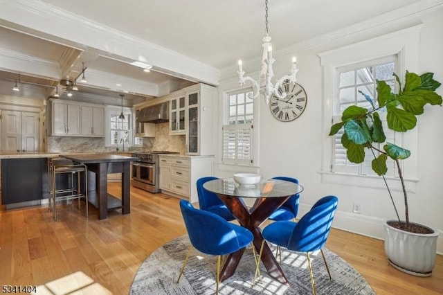 dining room featuring coffered ceiling, an inviting chandelier, ornamental molding, light wood-style floors, and beamed ceiling