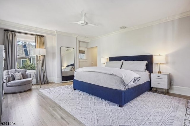 bedroom with visible vents, baseboards, light wood finished floors, and ornamental molding