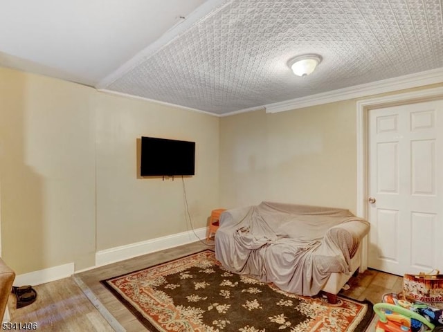 living room featuring a textured ceiling, wood finished floors, baseboards, and ornamental molding