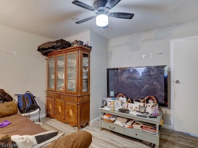 living room featuring light wood-style flooring, baseboards, and ceiling fan