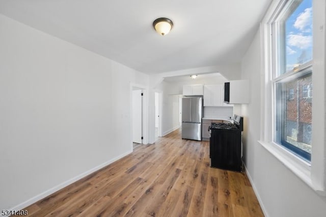 living area with light wood-style flooring, a wealth of natural light, and baseboards