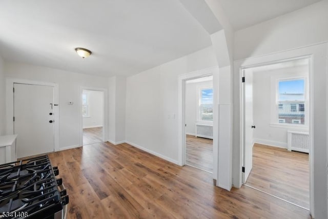 foyer entrance with baseboards, plenty of natural light, radiator heating unit, and wood finished floors