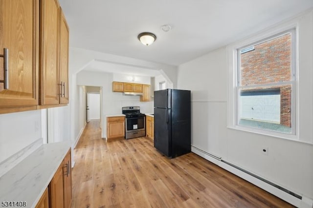 kitchen with a baseboard radiator, light wood-style flooring, under cabinet range hood, stainless steel gas range, and freestanding refrigerator