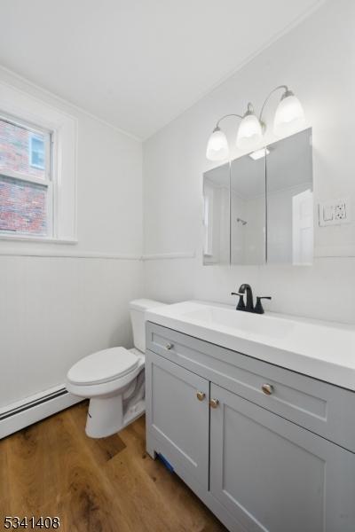 bathroom featuring a baseboard radiator, vanity, toilet, and wood finished floors