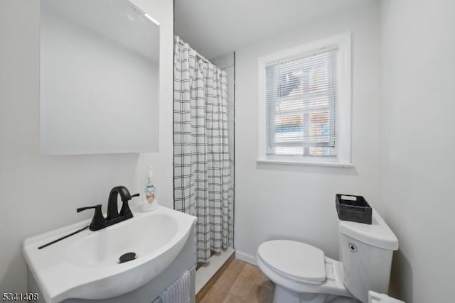 full bathroom with baseboards, a shower with shower curtain, toilet, wood finished floors, and a sink