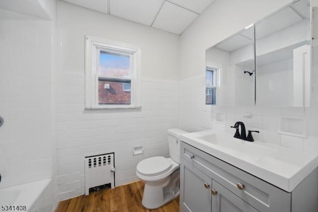 bathroom featuring tile walls, radiator, toilet, vanity, and wood finished floors